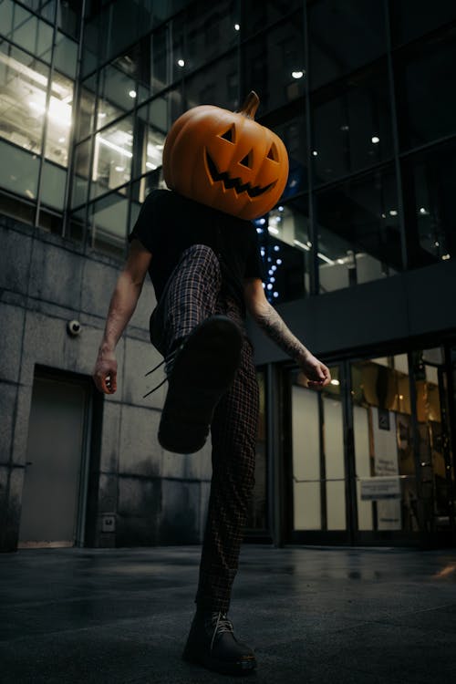 Low Angle Shot of a Man Wearing a Carved Pumpkin on His Head