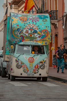 A vibrant, art-decorated vintage bus driving through the historic streets of Cuenca, Ecuador.