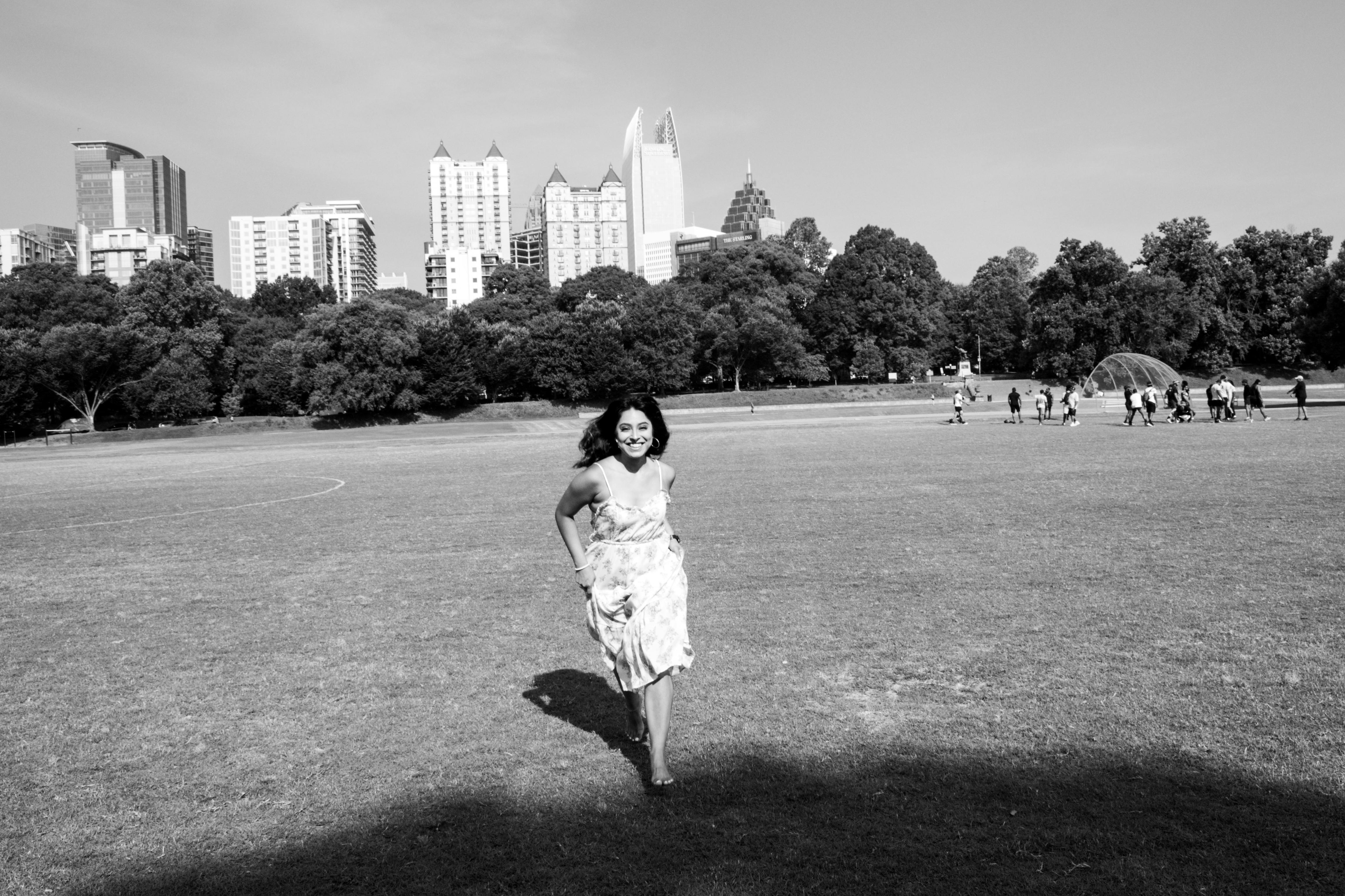 A joyful woman running in Piedmont Park with Atlanta skyline in background.