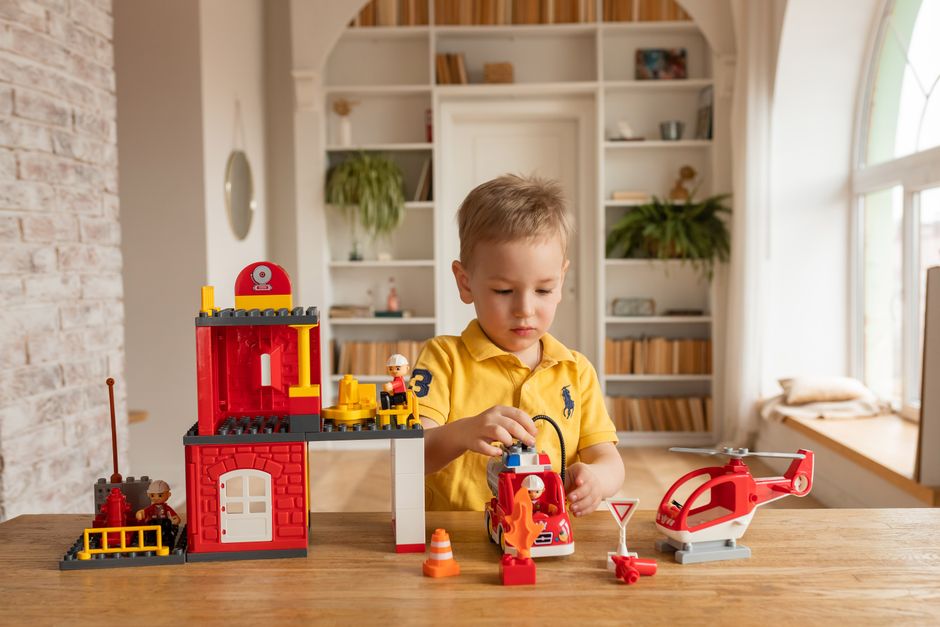 Photo by Polesie Toys on Pexels Young boy enjoys playing with toy fire station set indoors, promoting creativity and imagination. - Photo by Polesie Toys on Pexels