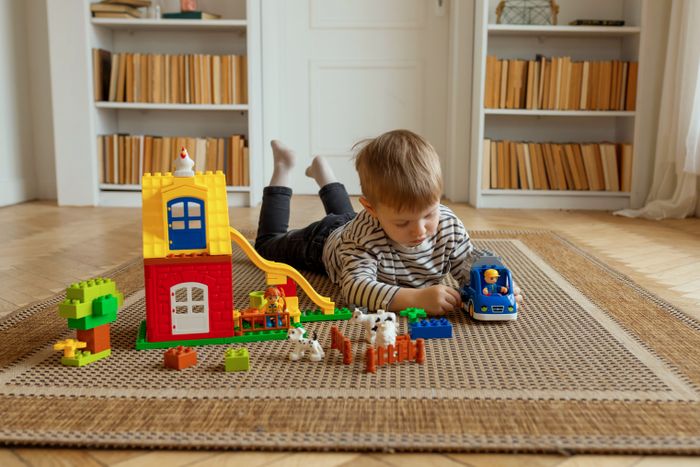 Blonde toddler playing with colourful building blocks and a toy car
