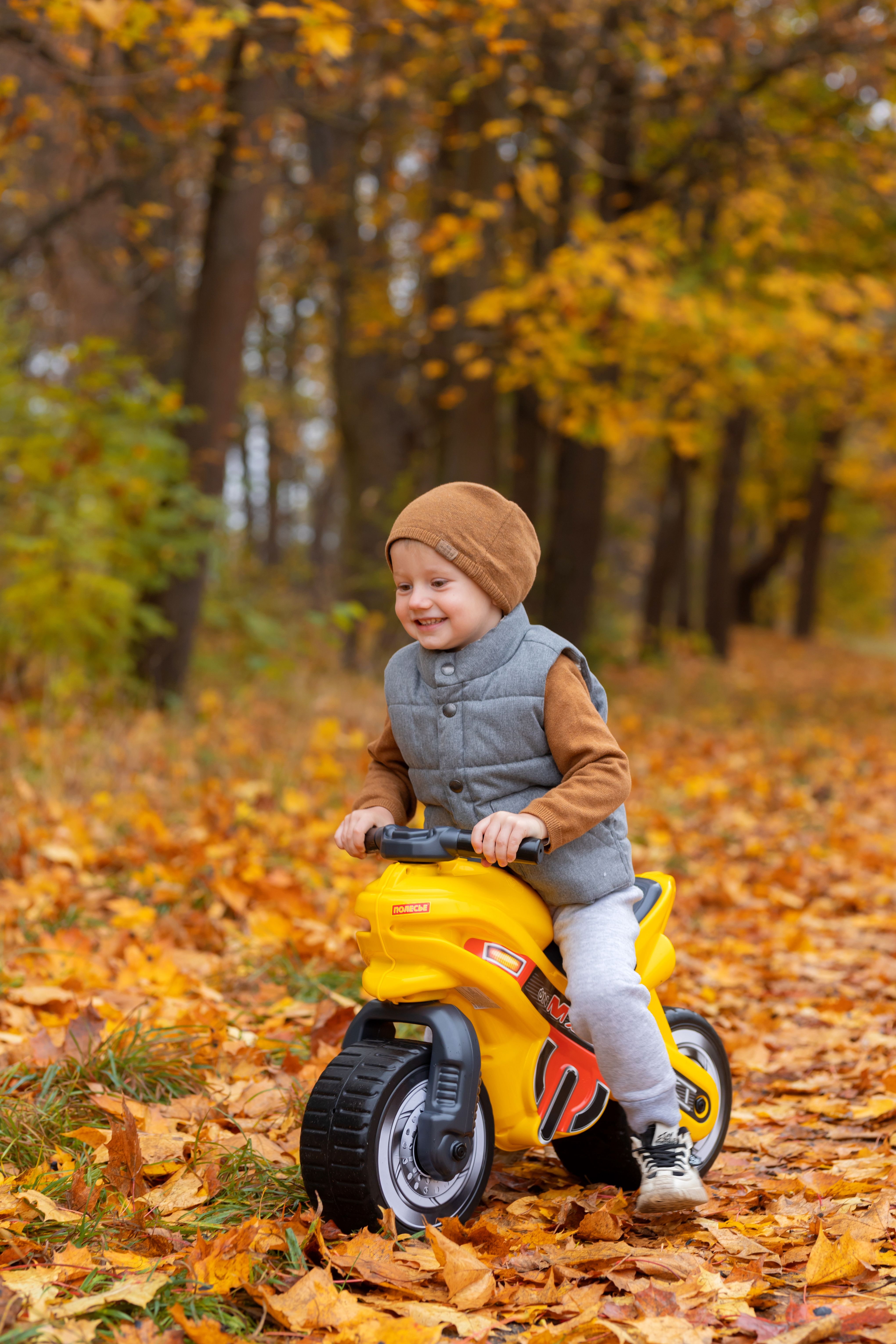 Boy Riding on a Toy Motorcycle in a Forest in Fall · Free Stock Photo