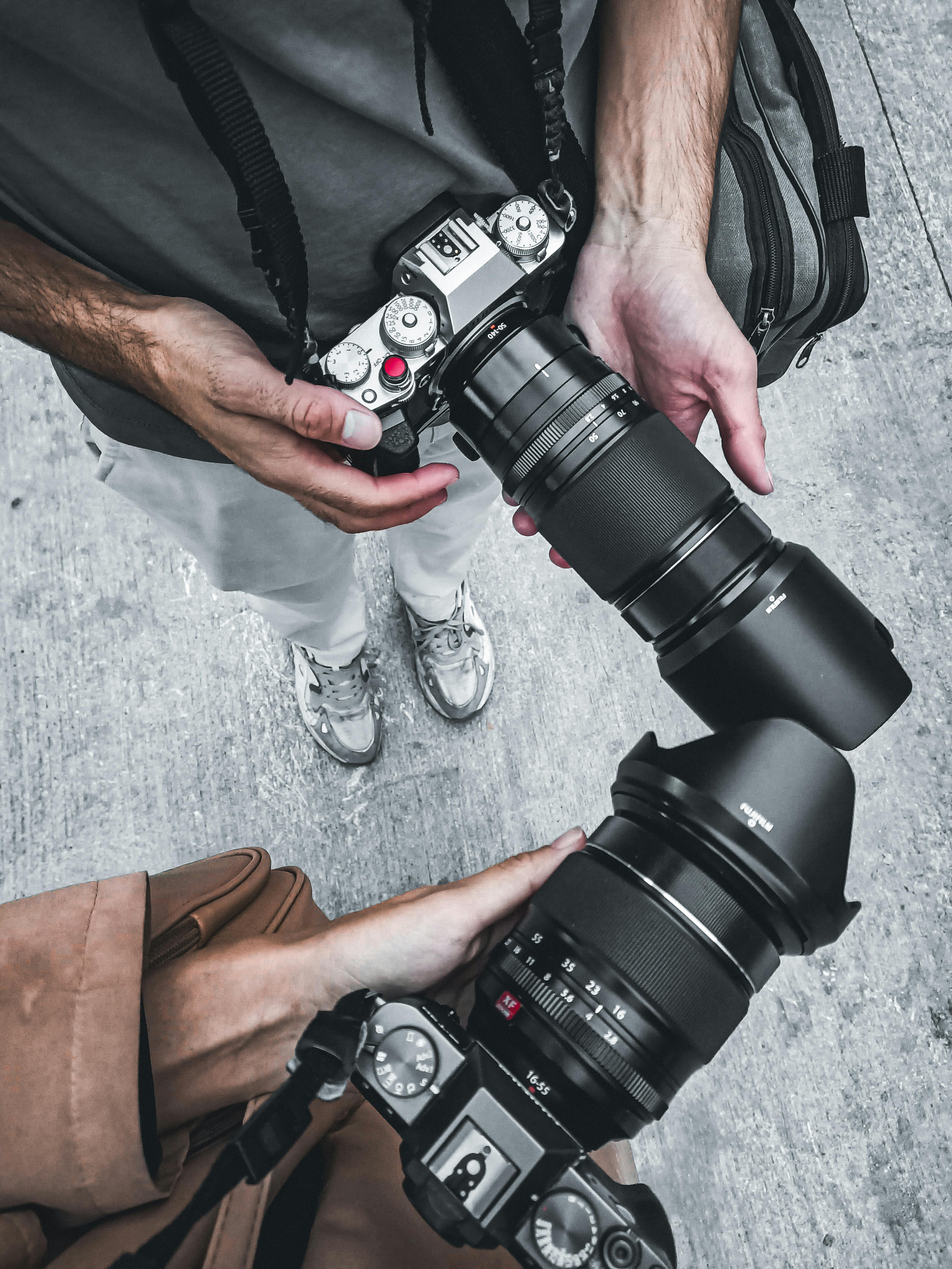 Free Top view of two photographers holding professional cameras and lenses outdoors. Stock Photo