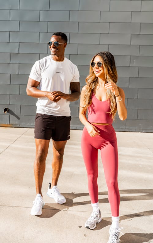 Smiling Woman in a Pink Tank Top and Leggings with a Man in White T-shirt and a Black Shorts