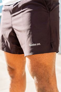 Close-up photo of a man in black shorts with 'bamboo ave.' branding, outdoors.