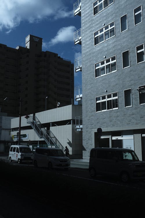 Cars Parked in Shadow by Sunlit Buildings in Town