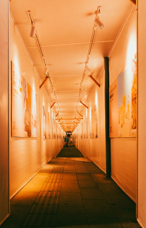 Free A warmly lit corridor showcasing posters on both sides, leading into the distance. Stock Photo
