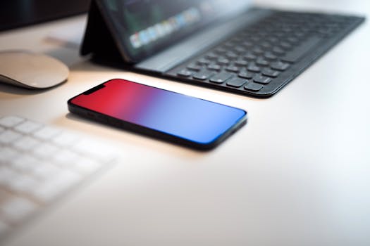 Close-up of a sleek smartphone and keyboard on a contemporary desk, ideal for tech and work themes.