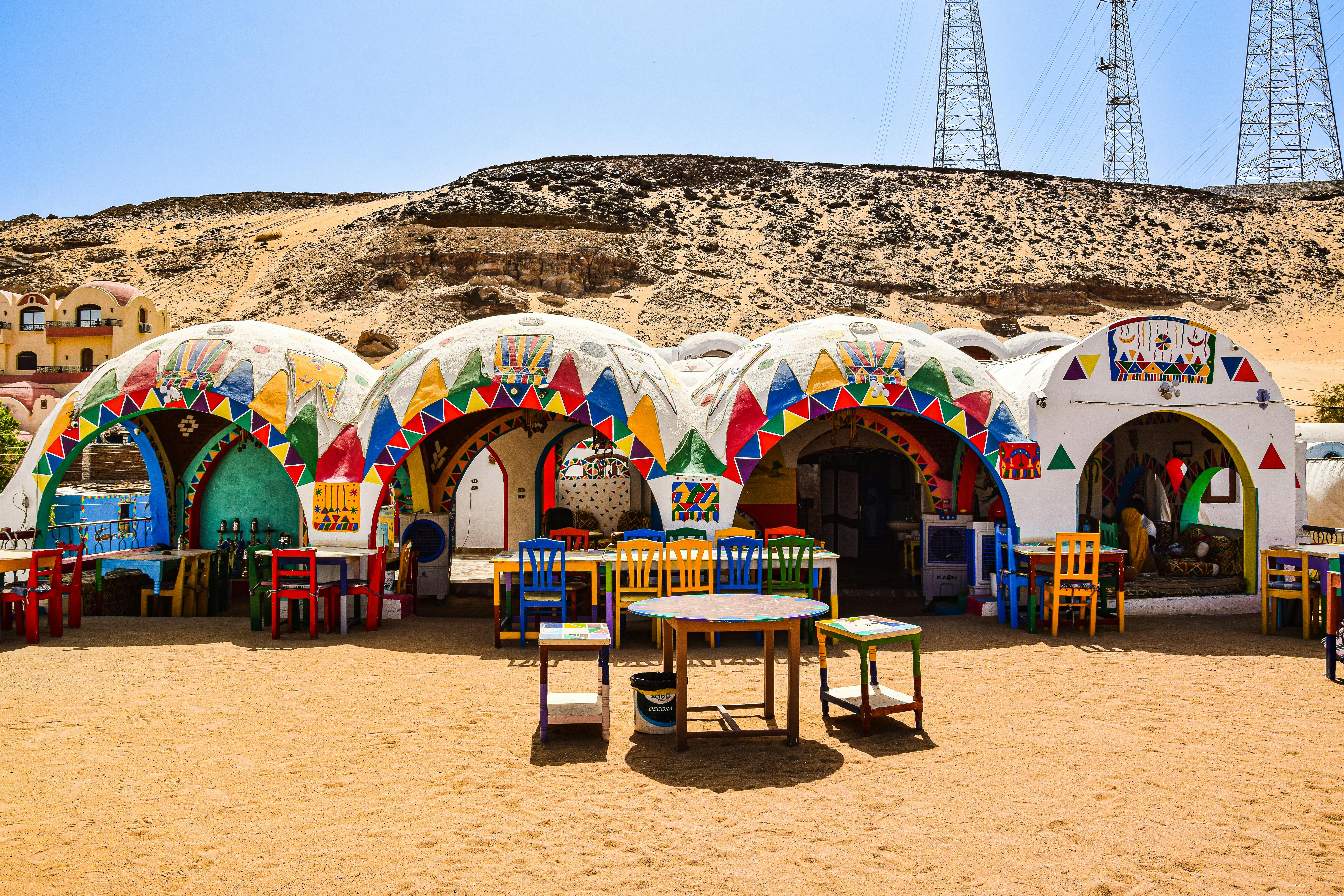Vibrant Nubian houses with multi-colored decorations in the Egyptian desert under a clear blue sky.