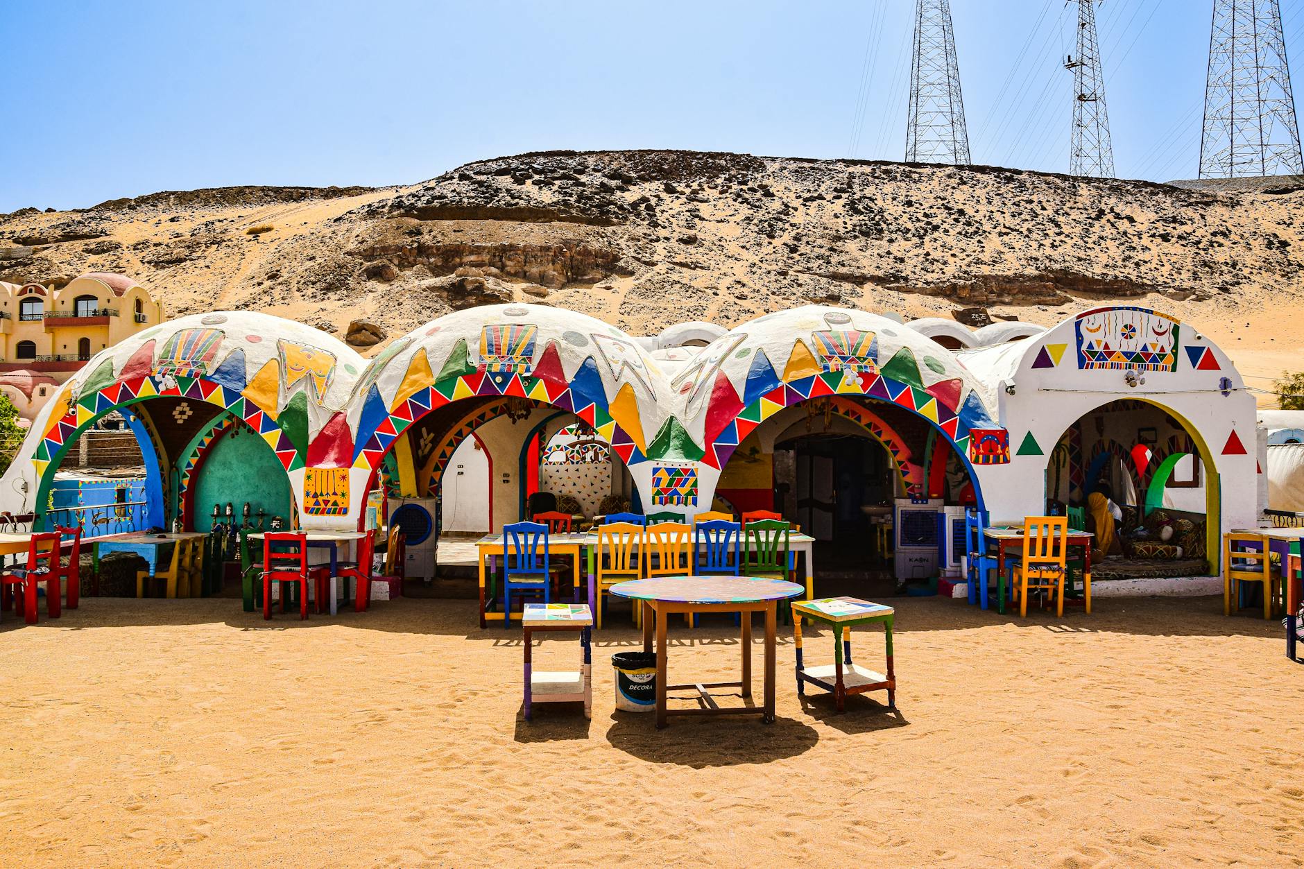 Vibrant Nubian houses with multi-colored decorations in the Egyptian desert under a clear blue sky.