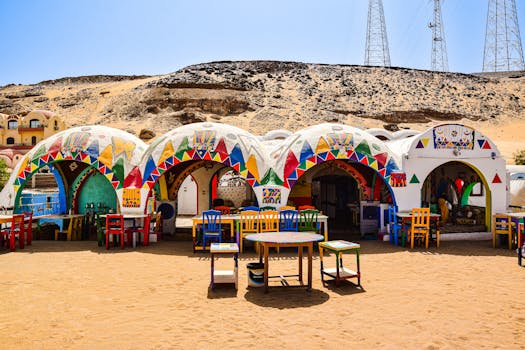 Vibrant Nubian houses with multi-colored decorations in the Egyptian desert under a clear blue sky.