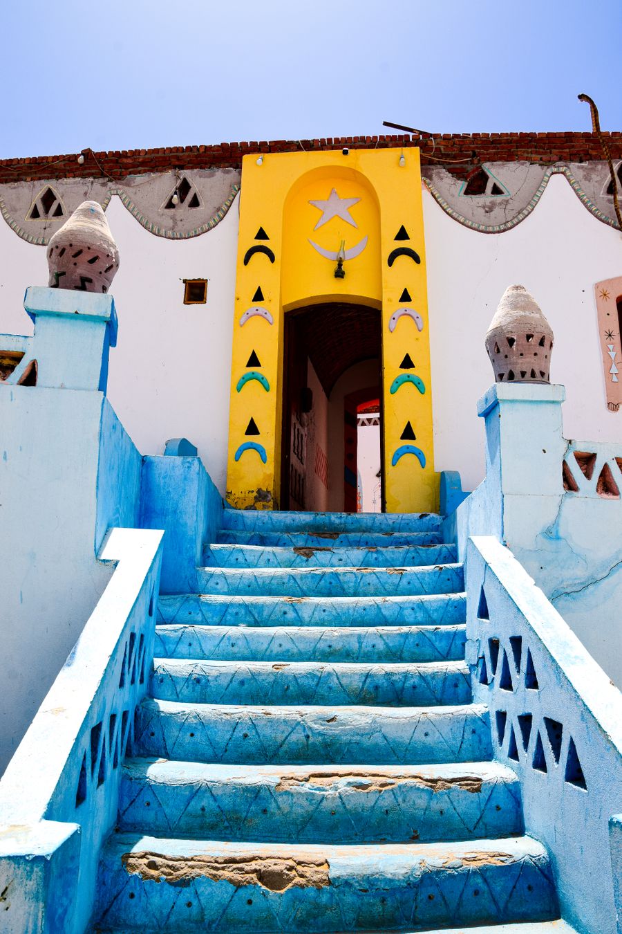 Escada azul e porta amarela numa vila núbia de Aswan
