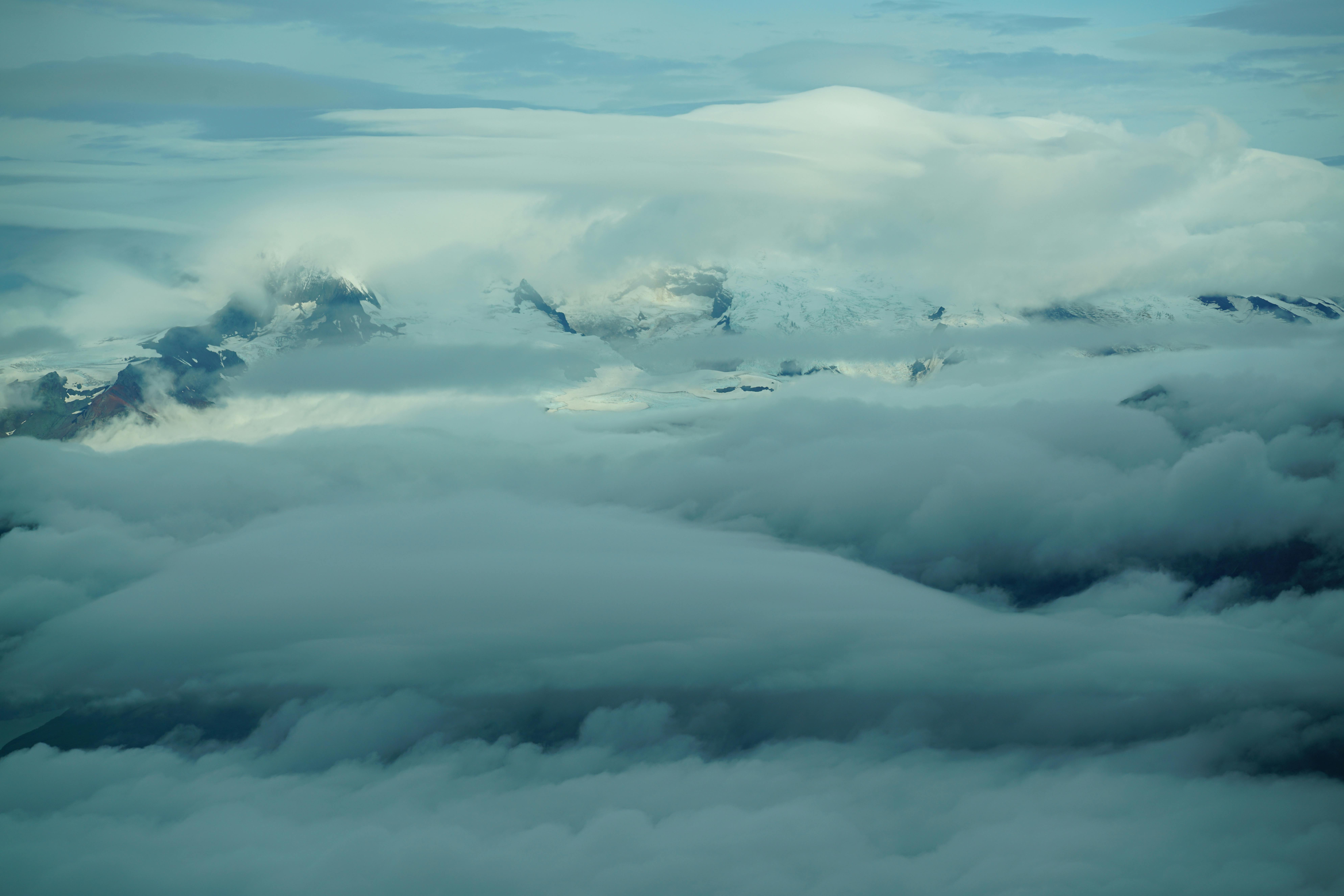 Majestic snow-capped mountains enveloped by clouds, creating a serene landscape.