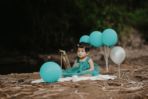 A Little Girl in a Dress Sitting among Birthday Decorations 