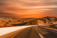 在迷人的日落天空下，空旷的高速公路蜿蜒穿过沙漠丘陵