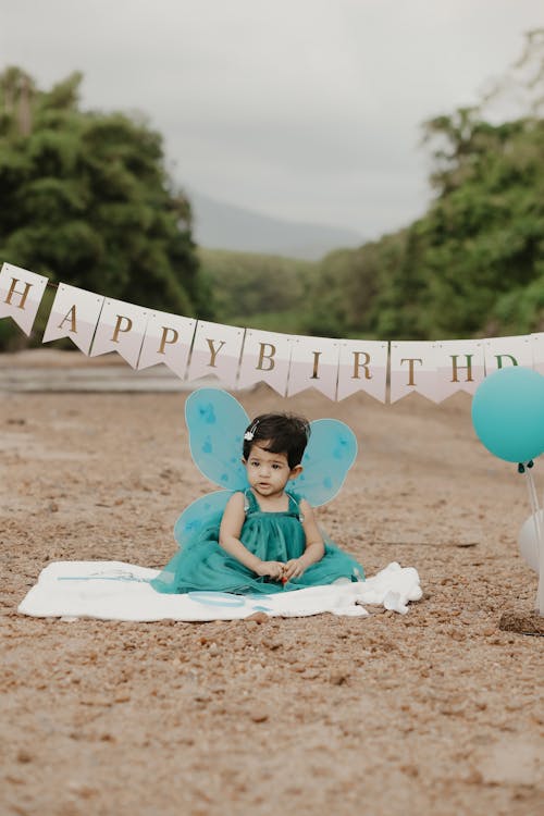 Free Girl Sitting in Green Dress and with Birthday Wishes behind Stock Photo