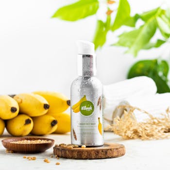 Bright product shot of banana cream face wash with natural elements and copy space.