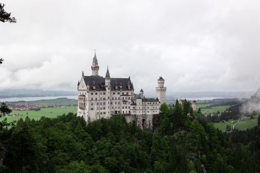 A stunning aerial view of Neuschwanstein Castle amidst lush forests in Schwangau, Bavaria.