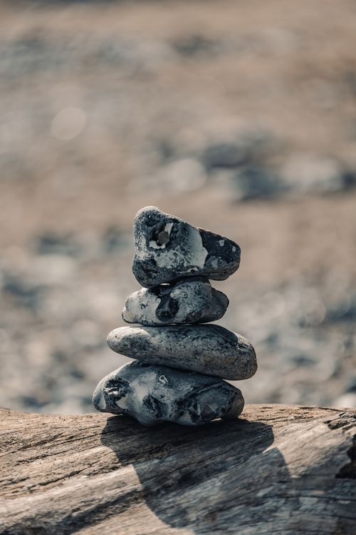 Free A harmonious stack of stones on wood against a blurred natural background, exuding a sense of balance. Stock Photo