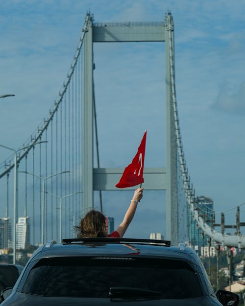 Woman with Flag of Turkey in Raised Arm in Car on Bridge in Istanbul