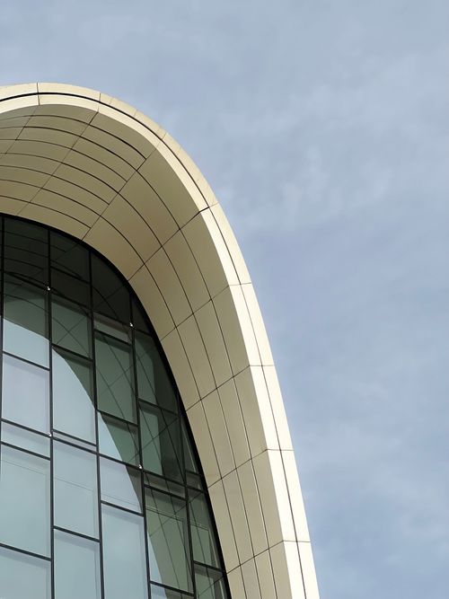 Free Close-up of the Heydar Aliyev Center's modern architectural design showcasing its sleek, curved lines and reflective windows. Stock Photo