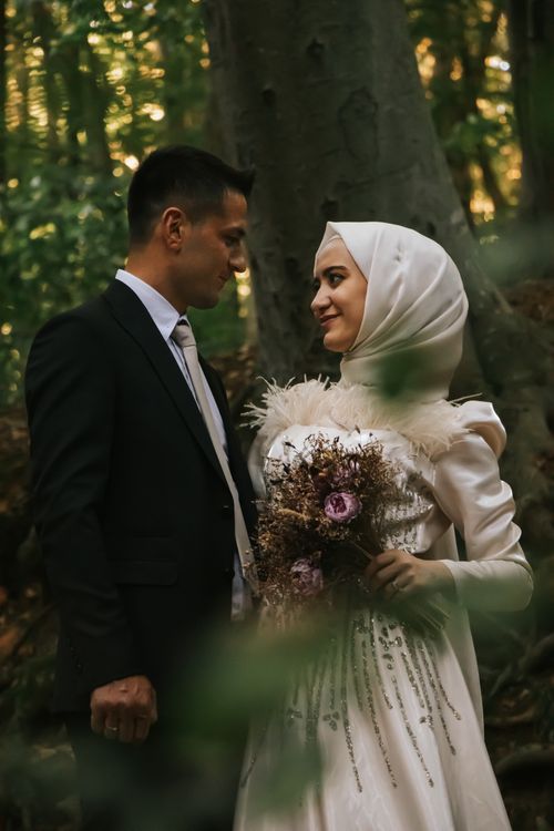 Free A couple's romantic moment captured in İstanbul. They are newlyweds in a serene forest setting, exuding elegance. Stock Photo