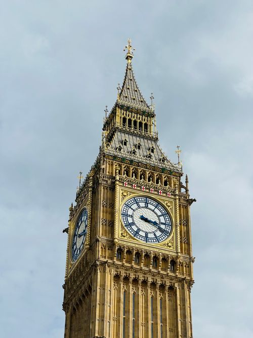 Free A close-up view of Big Ben clock tower in London, featuring intricate architectural details against a cloudy sky. Stock Photo