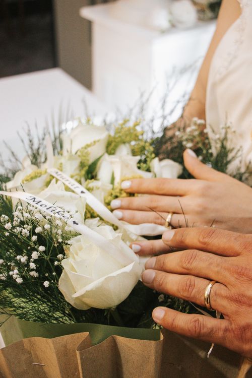 Free Close-up of bride and groom's hands with wedding rings on a bouquet of white roses. Stock Photo