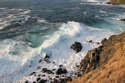 Free Vibrant ocean waves crashing against rugged rocks on a scenic coastline, showcasing nature's raw beauty. Stock Photo