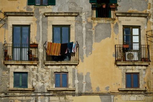 Free A rustic building facade with balconies, windows, and drying clothes, showcasing urban charm and character. Stock Photo