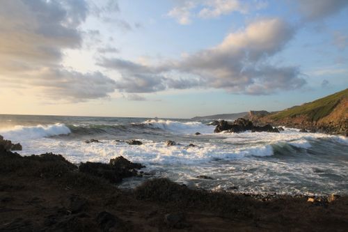 Free A stunning coastal scene featuring waves crashing against rocky shores under a bright sky. Stock Photo