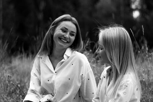 Black and White Photo of a Mother and a Daughter Sitting in Meadow