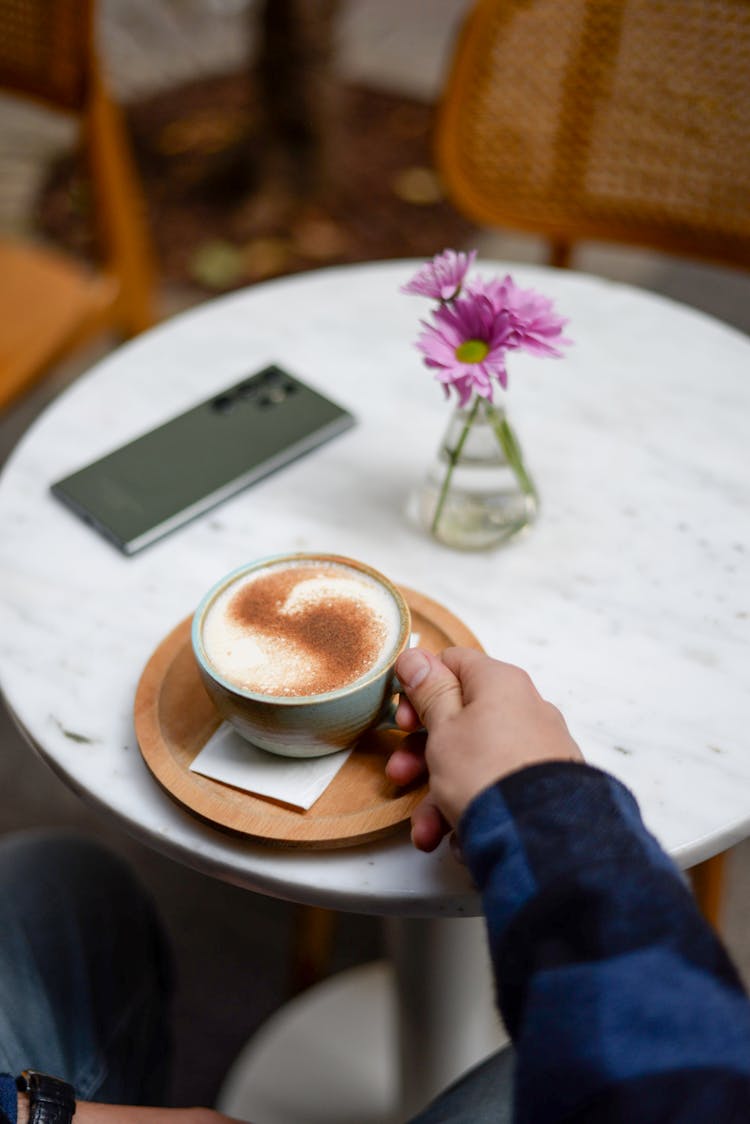 Man Sitting At The Table In A Cafe With A Cappuccino 