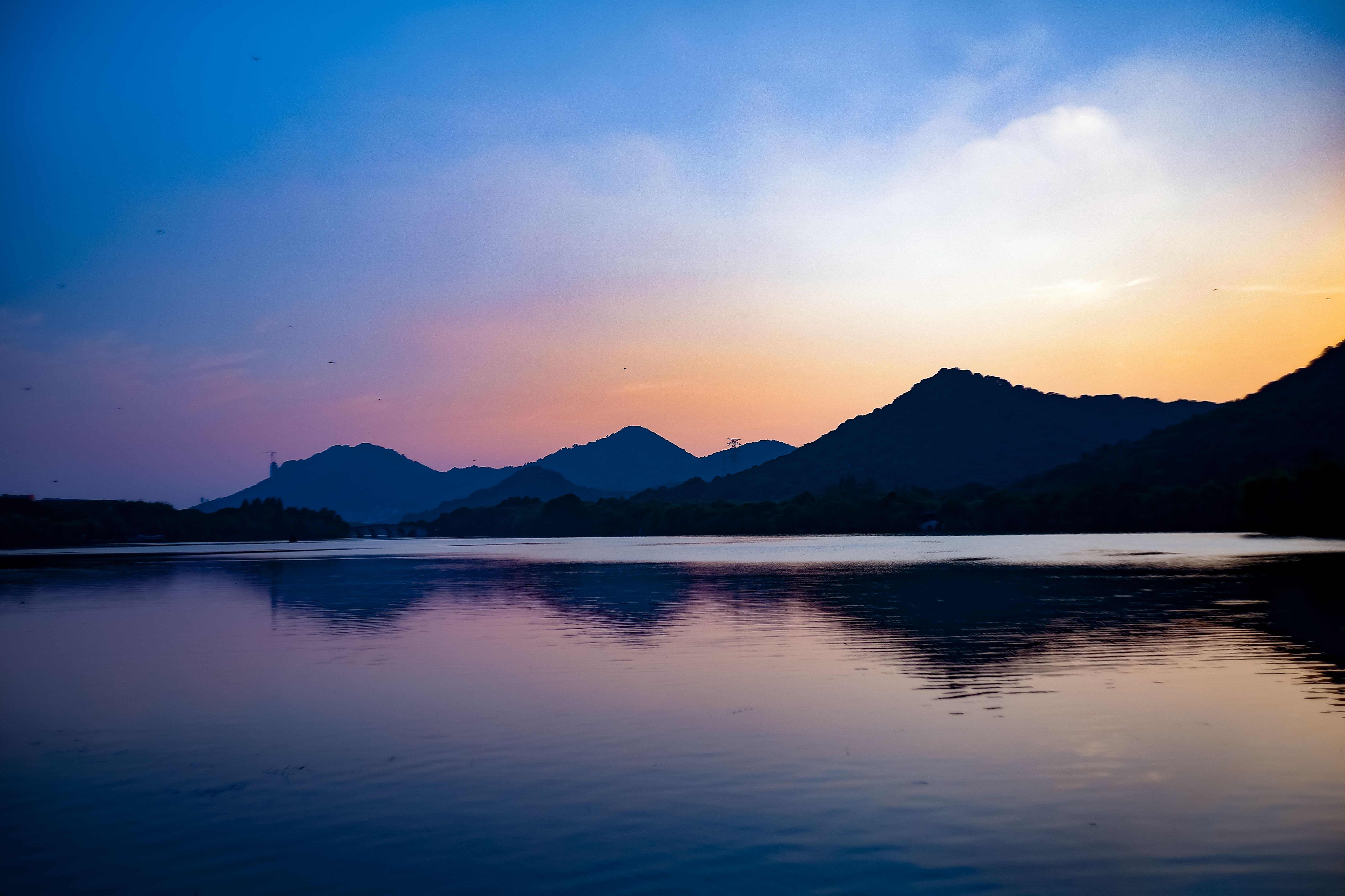 Powai Lake at dusk with the low hills and apartment towers of Hiranandani behind