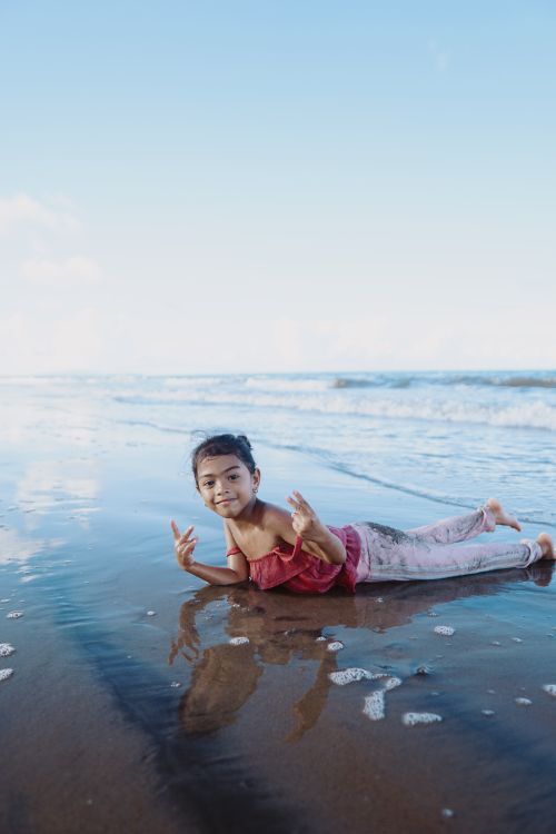 Free A child joyfully playing on a sandy beach in Abuyog, Philippines, under a clear sky. Stock Photo