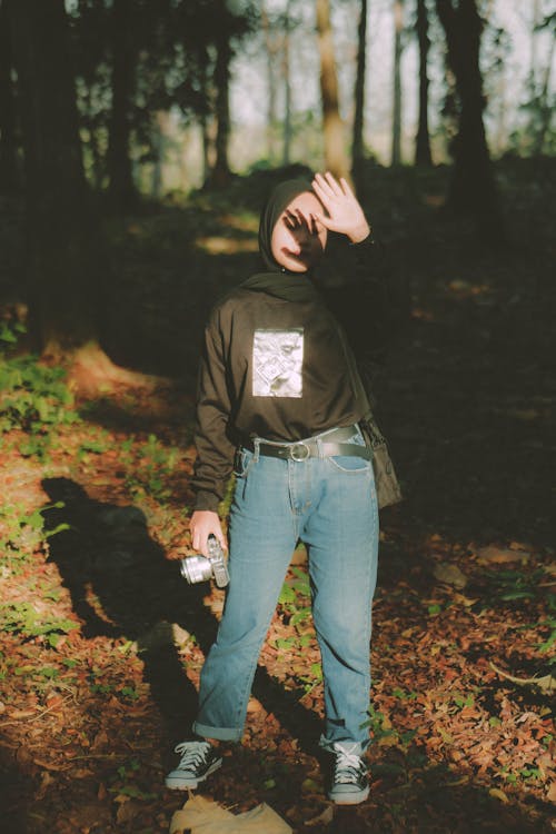 Woman in Hijab Standing with Camera in Forest