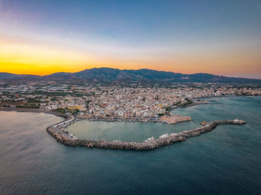 Unforgettable Fly Over Athens City & Riviera by Helicopter Review: The Ultimate Aerial Experience in Greece Review 2026 - Breathtaking aerial shot of Ierapetra harbor and cityscape during the sunset in Greece.