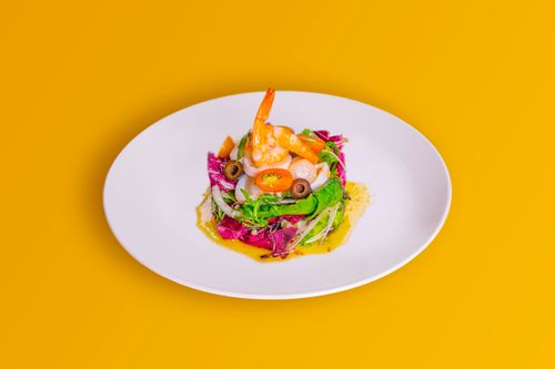 Free Vibrant shrimp salad with mixed greens on a vivid yellow backdrop. Stock Photo