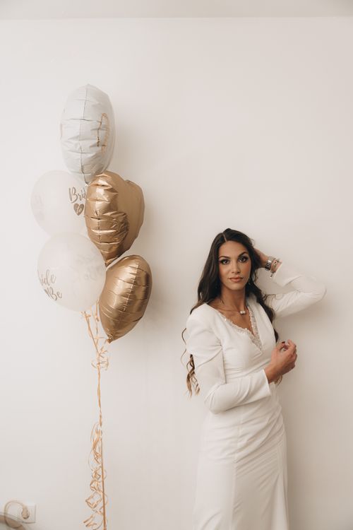 Free A stylish bride in a white dress stands with heart-shaped balloons, exuding elegance and joy. Stock Photo