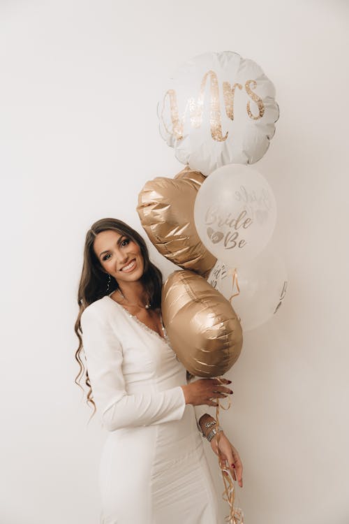 Woman in a White Dress Holding Balloons