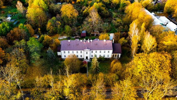 Aerial shot of a mansion surrounded by vibrant autumn trees. Perfect for nature and real estate themes.