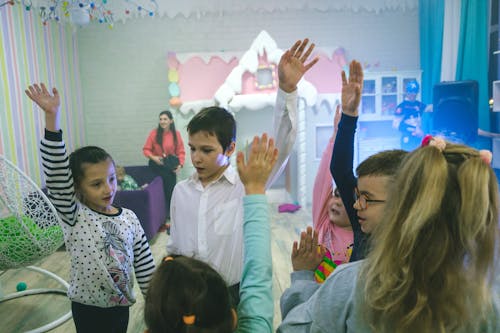 Children Celebrating Friend's Birthday - Happy Kids Raising Hands in Joyful Celebration