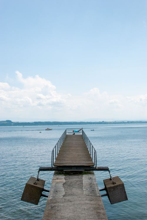 Free Peaceful view of an empty pier extending into a serene lake under a clear sky. Stock Photo