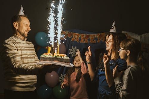 Heartwarming birthday event as a father presents a huge cake adorned with enormous candles, sparking joy in his happy daughter as she makes a wish. magic of a daughter's birthday dream com...
