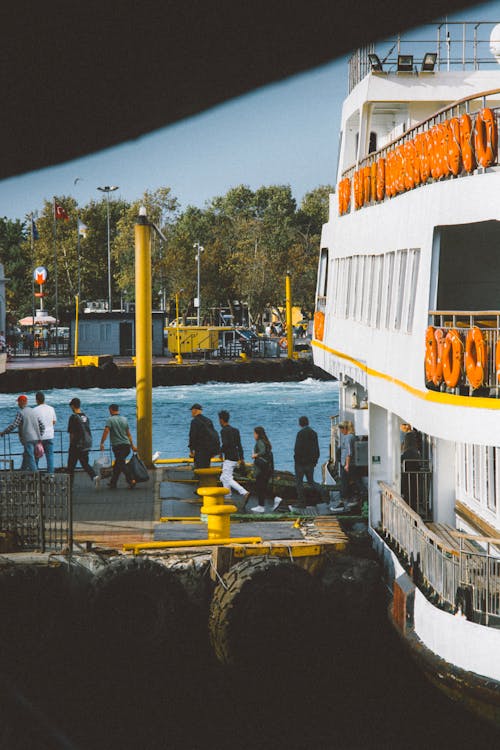 People Walking on Pier with Moored Ferry