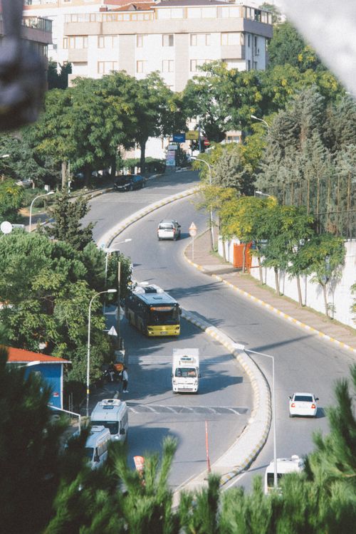 Free Aerial view of a busy curved street with traffic and greenery in a city setting. Stock Photo