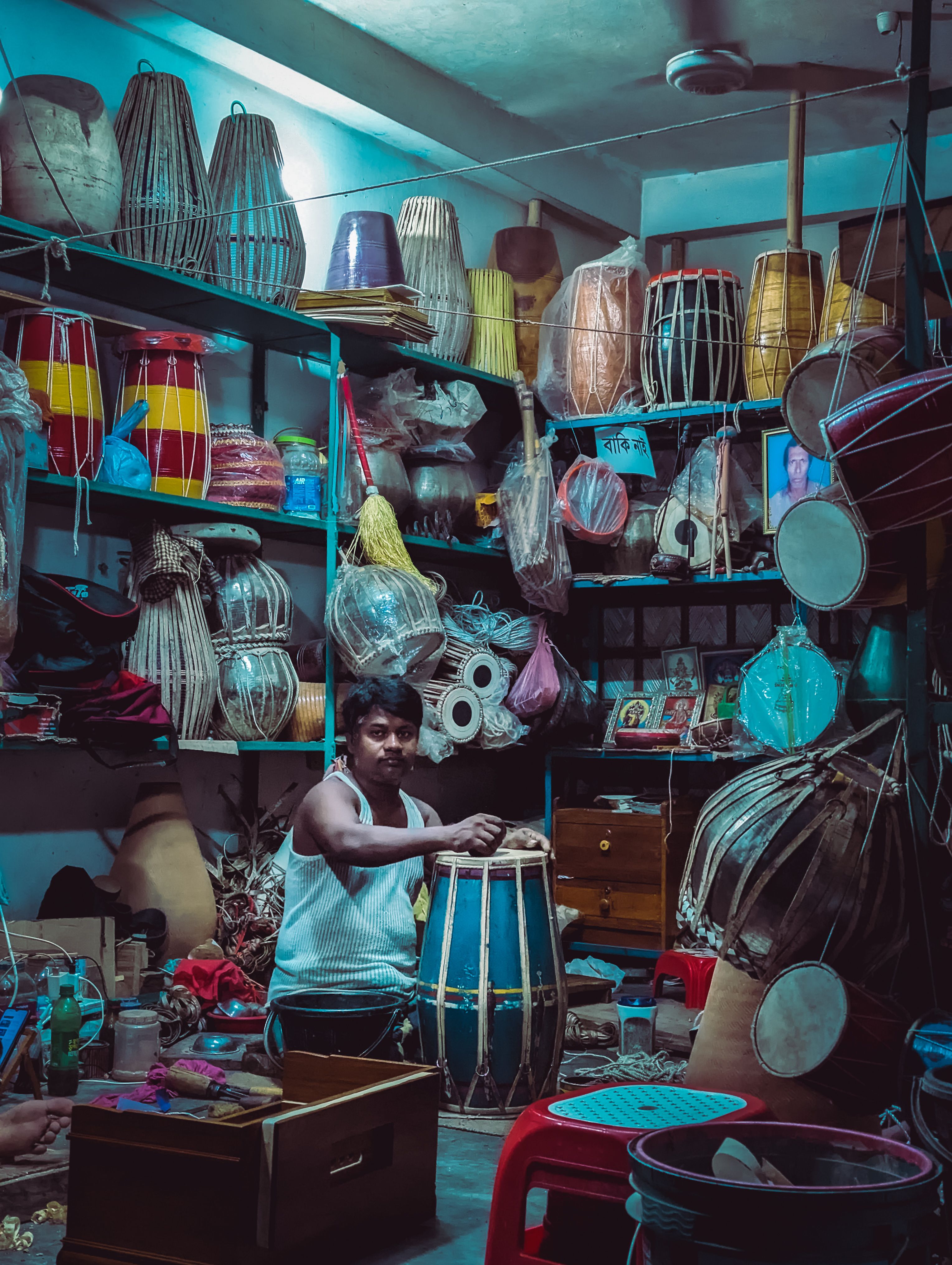 A craftsman working on a handmade drum in a vibrant workshop filled with traditional musical instruments.