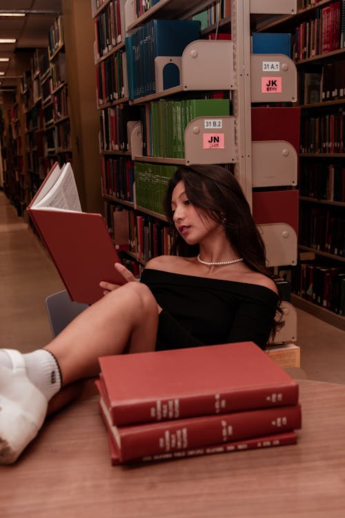 Woman Sitting with Leg on Table at Library and Reading