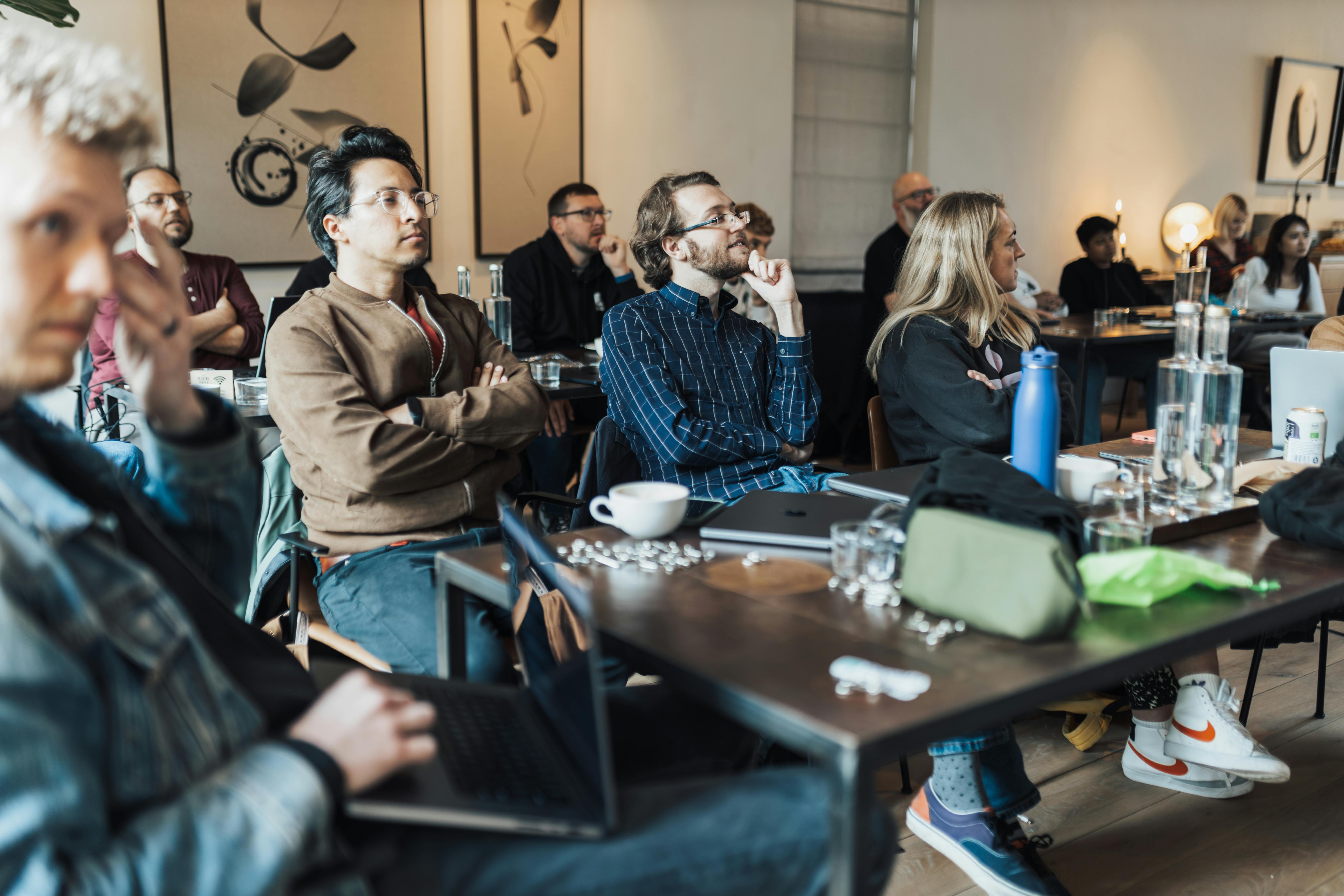 Adult volunteers seated in a round-table workshop listening to a trainer