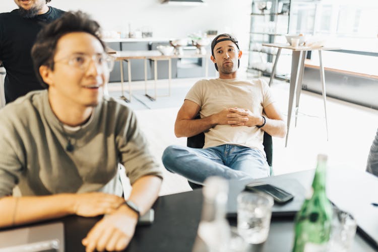 Young Men Sitting At The Table In An Office And Talking 